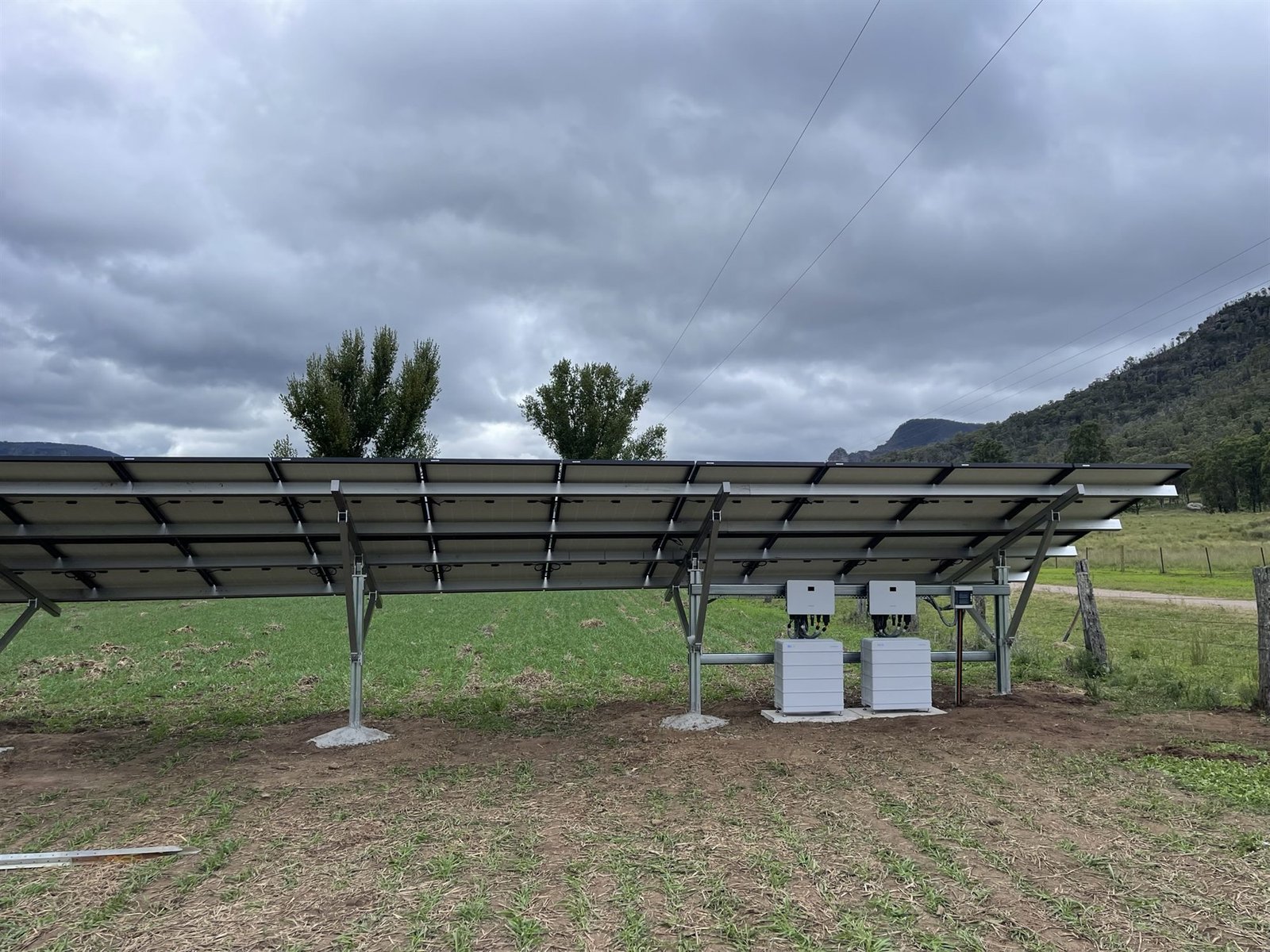 Off-grid solar array with battery and inverter cabinets in a rural Hunter Valley paddock