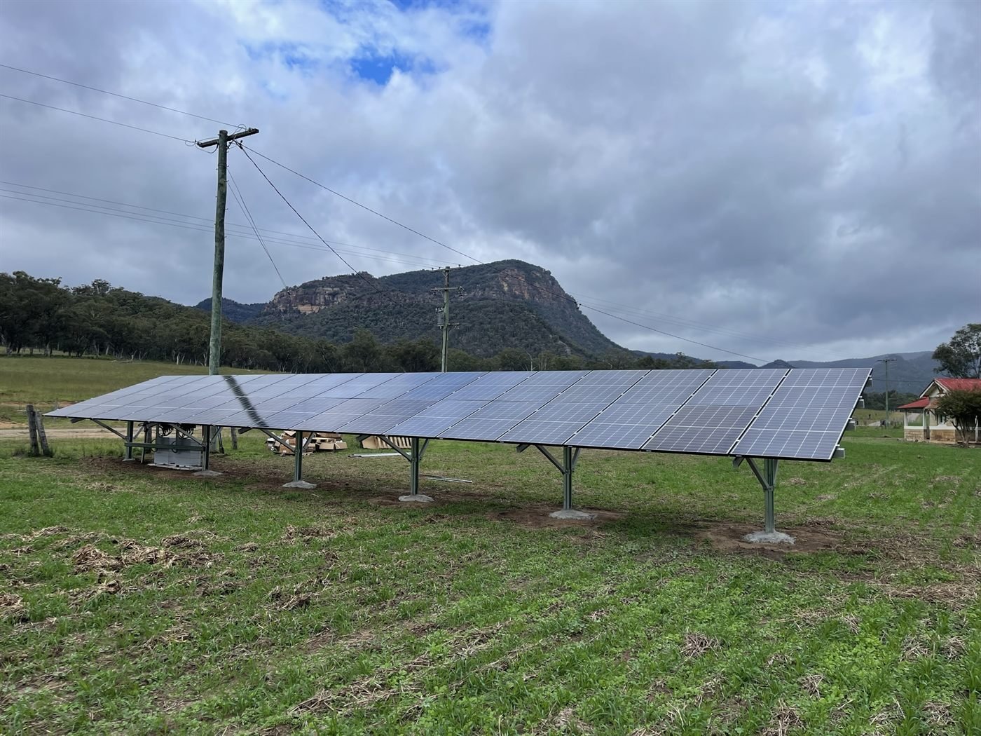 Off-grid ground-mount solar array with sandstone cliff backdrop